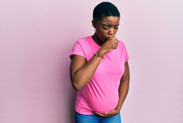 Jeune femme enceinte, touchant son ventre, se sentant mal et toussant